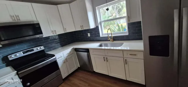 a kitchen with granite countertop a stove a sink and a microwave