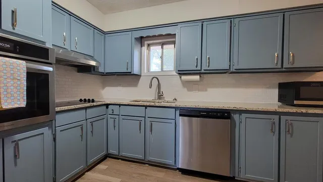 a kitchen with stainless steel appliances granite countertop white cabinets sink and dishwasher