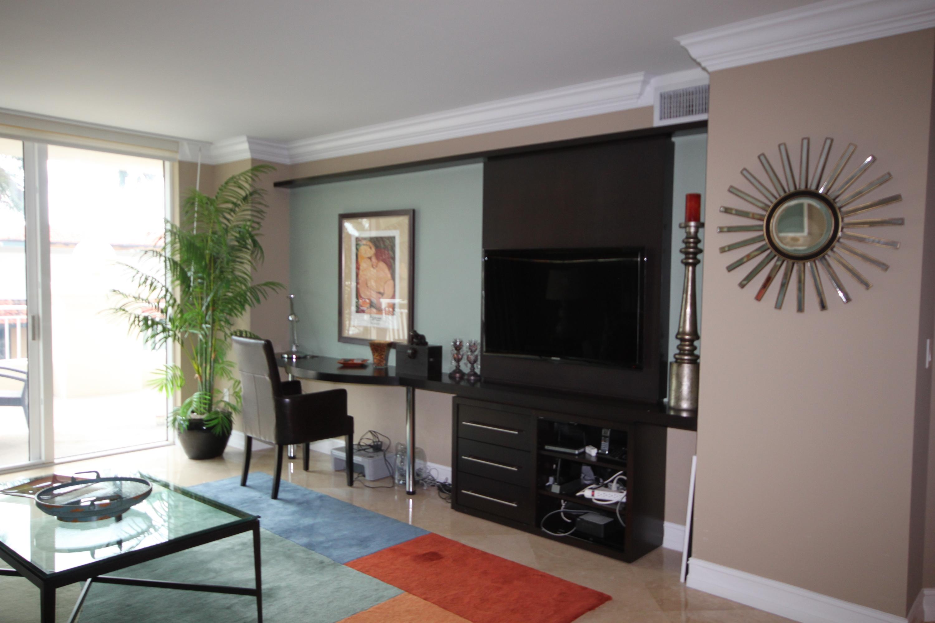 99 Southeast Mizner Boulevard, Unit 219 Boca Raton, FL 33432 - Photo 7 of 14 a living room with furniture a flat screen tv and a fireplace