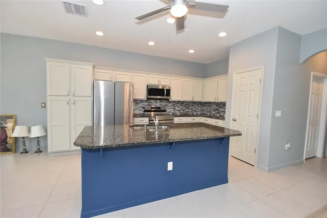 a kitchen with kitchen island granite countertop a sink and refrigerator