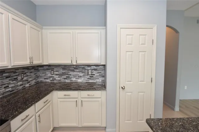 a kitchen with granite countertop white cabinets and sink