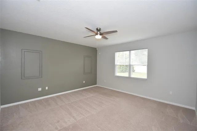 an empty room with a window and a ceiling fan