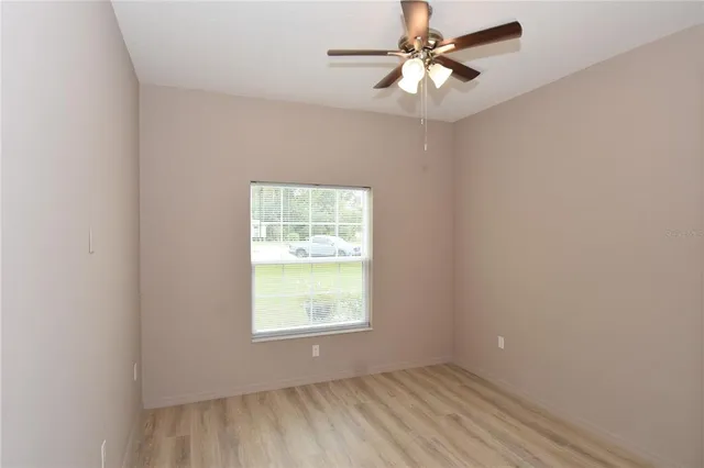 an empty room with a window and a fan