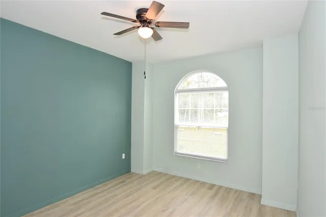 a view of empty room with wooden floor and fan