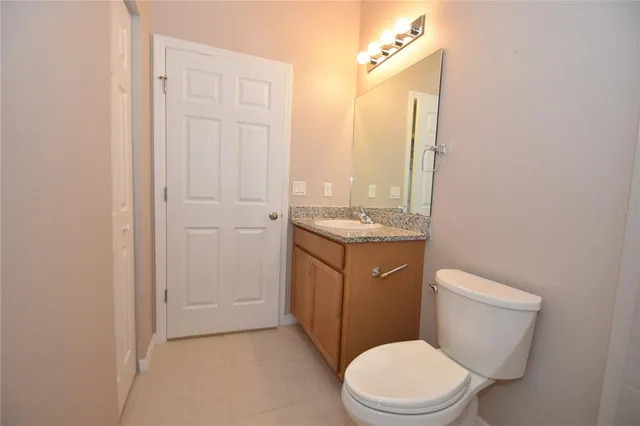 a bathroom with a granite countertop toilet sink and mirror