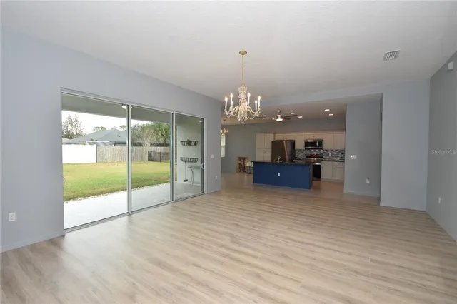 a large room with kitchen view and large windows