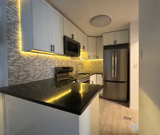 a kitchen with stainless steel appliances granite countertop a refrigerator a stove and a sink with wooden floor