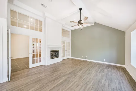 a view of an empty room with wooden floor fireplace and a window