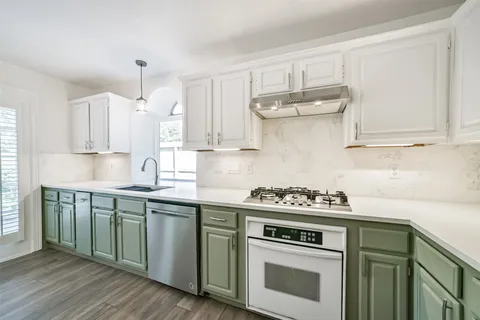 a kitchen with stainless steel appliances white cabinets and a stove top oven
