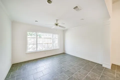 an empty room with a ceiling fan and window