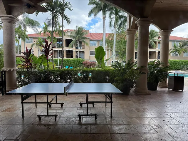 a view of a patio with table and chairs potted plants and palm tree