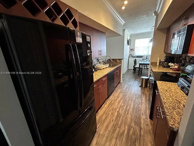 a kitchen with granite countertop a refrigerator stove and wooden floor
