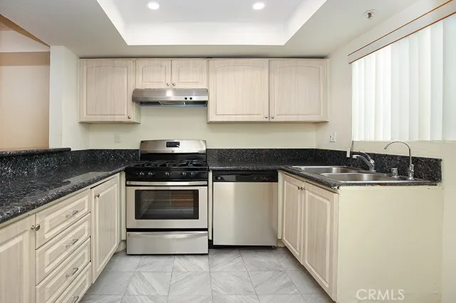 a kitchen with stainless steel appliances granite countertop a sink and a stove