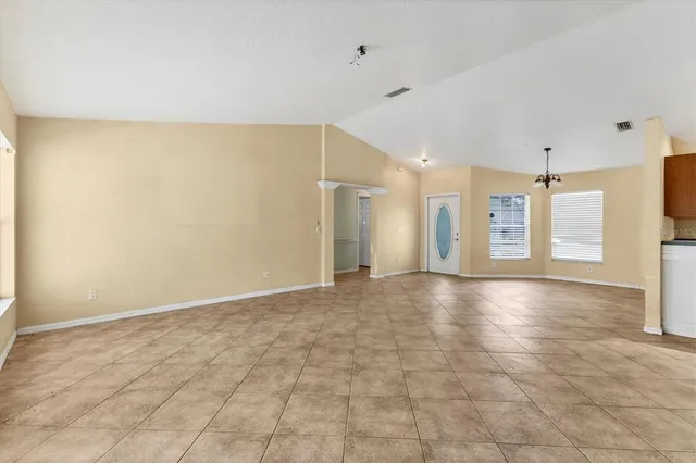 a view of an empty room with window and chandelier