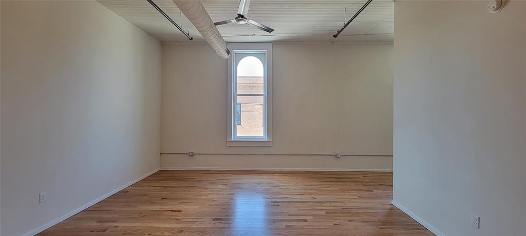 201 East Chambers Street, Unit 203 Cleburne, TX 76031 - Photo 6 of 8 an empty room with wooden floor and windows