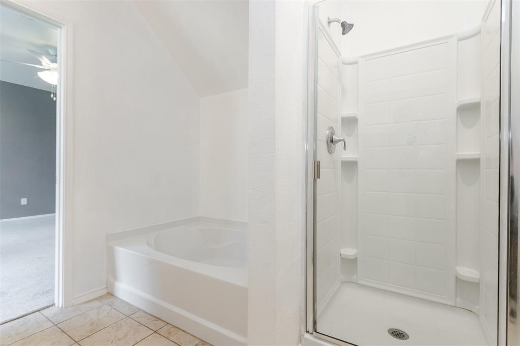 203 Arabian Road Waxahachie, TX 75165 - Photo 15 of 24 White tiled flooring complements a built-in soaking tub with a sloped ceiling above