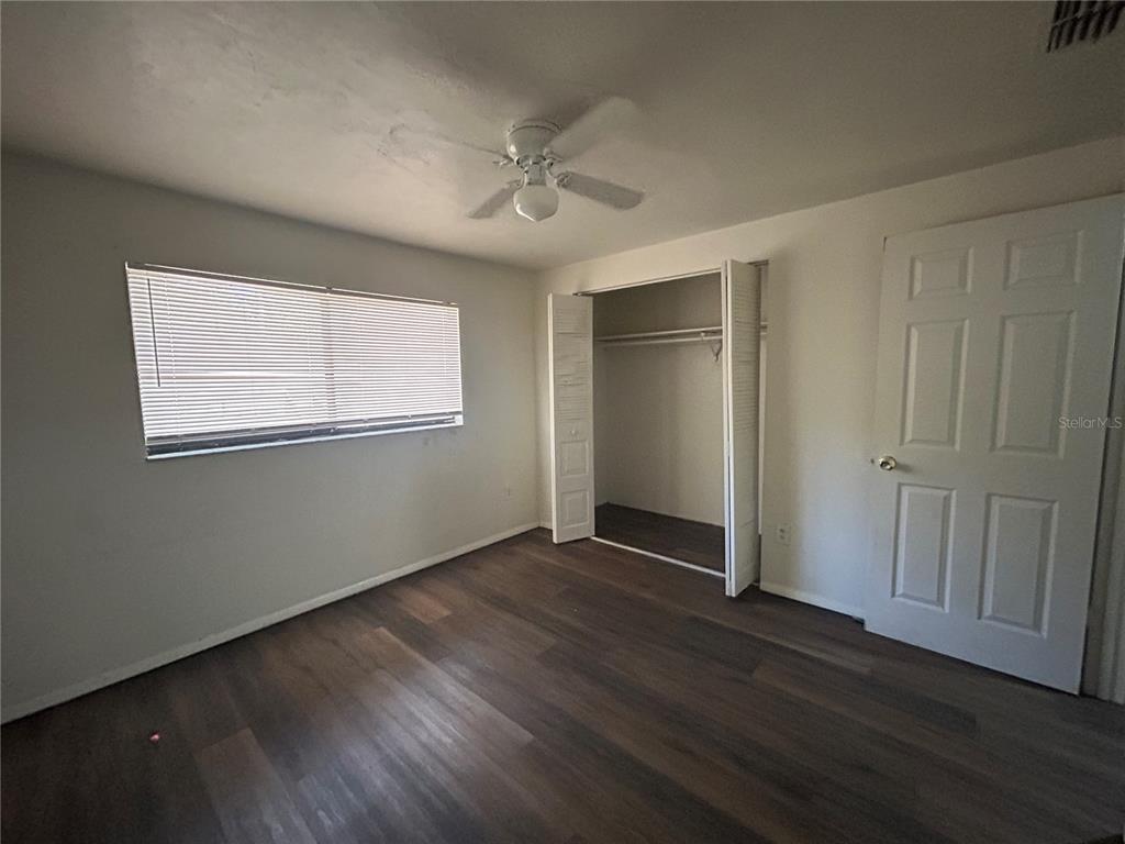 707 Southwest 68th Terrace, Unit A Gainesville, FL 32607 - Photo 8 of 16 an empty room with wooden floor chandelier fan and windows