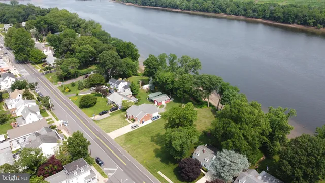 a view of a street with a yard and large trees