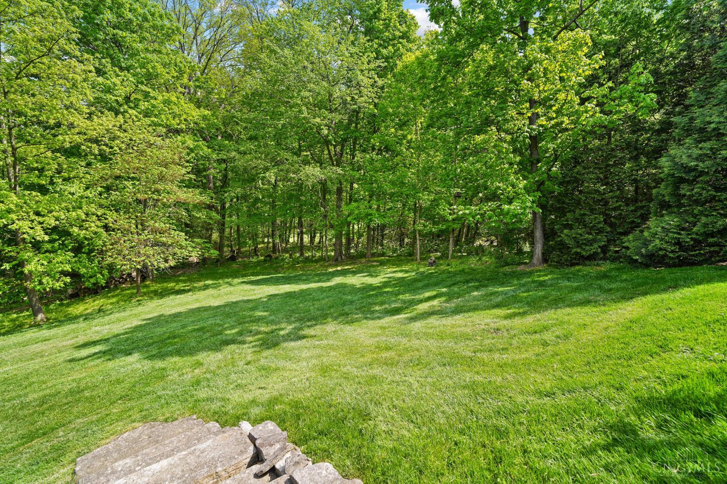 2780 Walsh Road Cincinnati, OH 45208 - Photo 57 of 68 The rear yard offers a beautiful blend of structure and natural serenity, with thoughtfully placed stepping stones and a stone stairway that gently guide you to a lush, expansive lawn. Set on a private 1.5-acre lot, the property is surrounded by mature trees, creating a peaceful, park-like setting with both open green space and wooded privacy—ideal for outdoor enjoyment, play or quiet retreat.