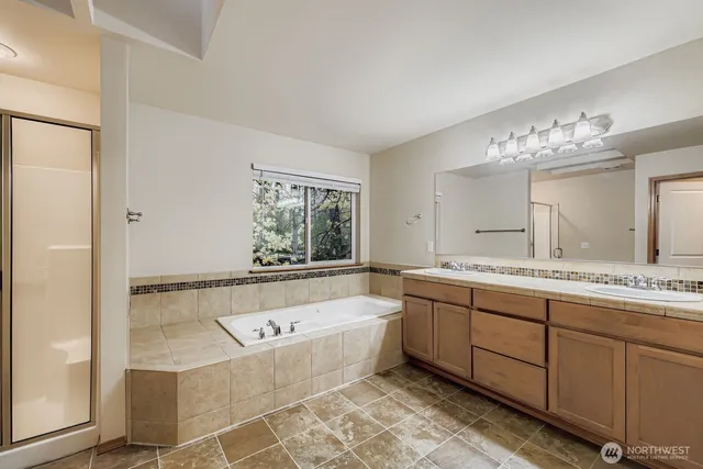 a bathroom with a bathtub a double vanity sink and mirror
