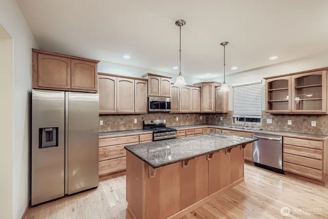 a kitchen with stainless steel appliances granite countertop a sink a stove a refrigerator a center island and cabinets