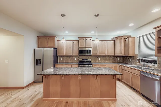 a kitchen with stainless steel appliances granite countertop a sink a stove a refrigerator and island