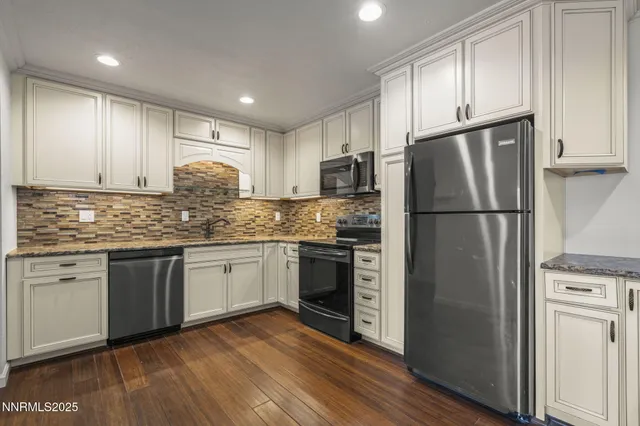 a kitchen with granite countertop stainless steel appliances a refrigerator a sink and cabinets