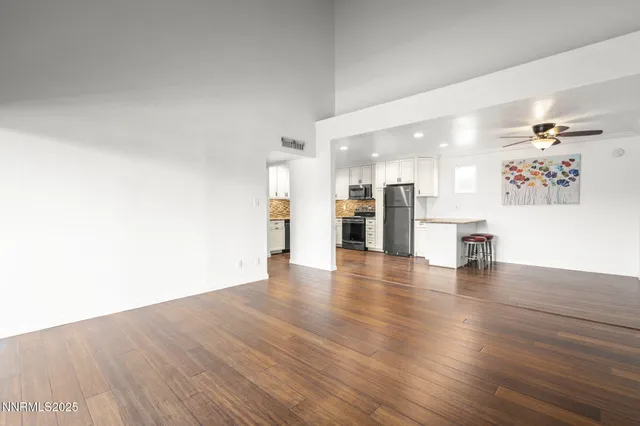 a view of a kitchen with a fridge and wooden floor