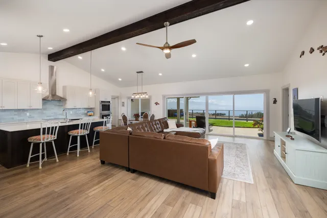 a living room with furniture kitchen area and a wooden floor