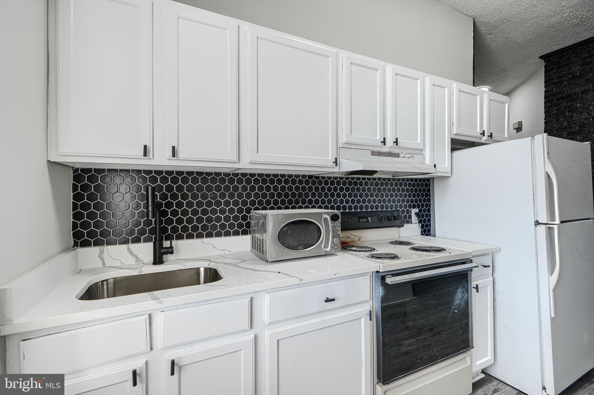 617 North Paca Street Baltimore, MD 21201 - Photo 11 of 20 a kitchen with a sink a refrigerator and cabinets