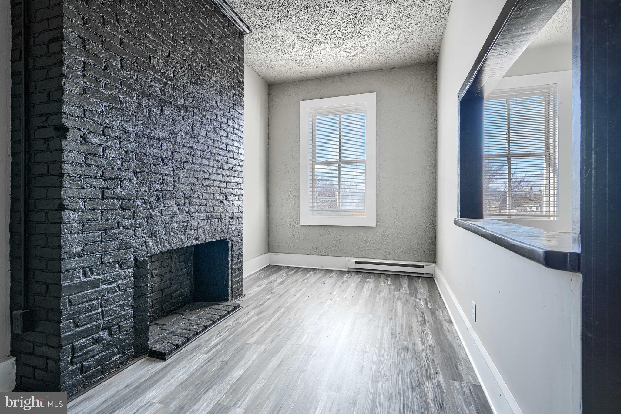 617 North Paca Street Baltimore, MD 21201 - Photo 7 of 20 an empty room with windows a fireplace and wooden floor