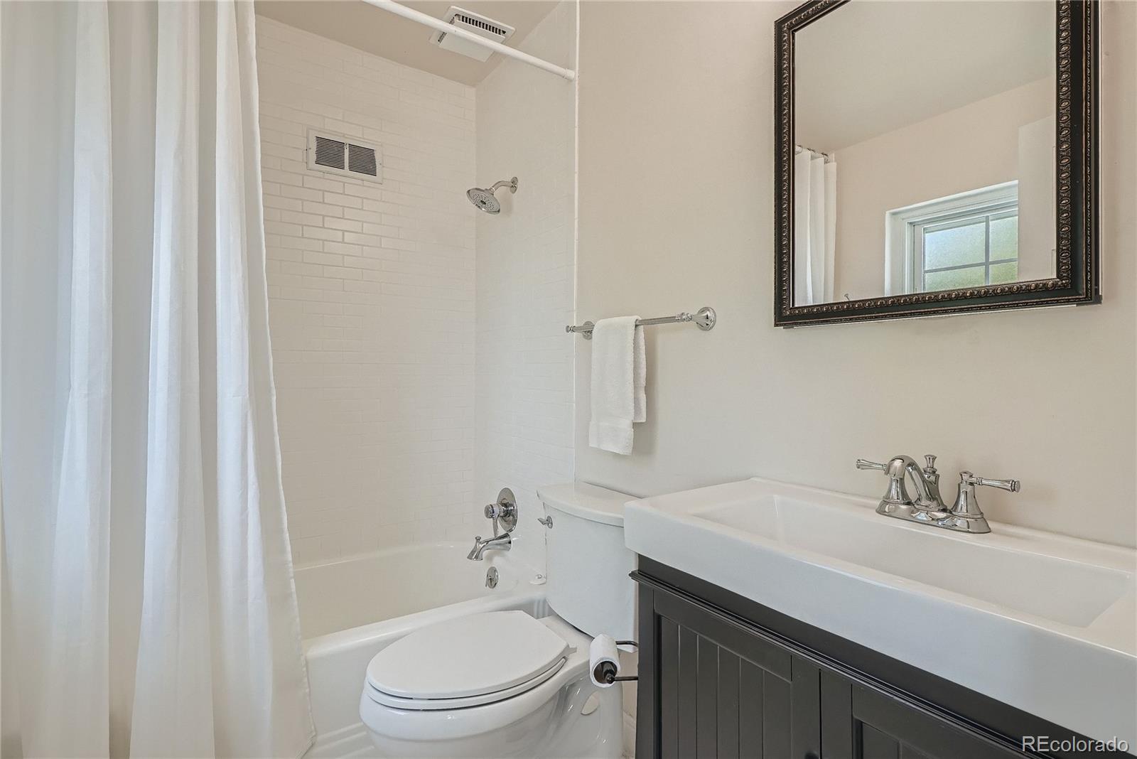 1209 West Ridge Road Littleton, CO 80120 - Photo 19 of 33 a bathroom with a sink toilet a mirror and shower