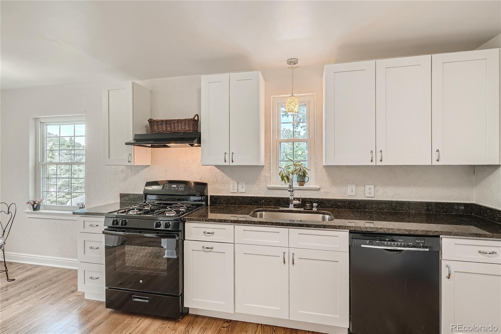 1209 West Ridge Road Littleton, CO 80120 - Photo 9 of 33 a kitchen with granite countertop white cabinets and black appliances
