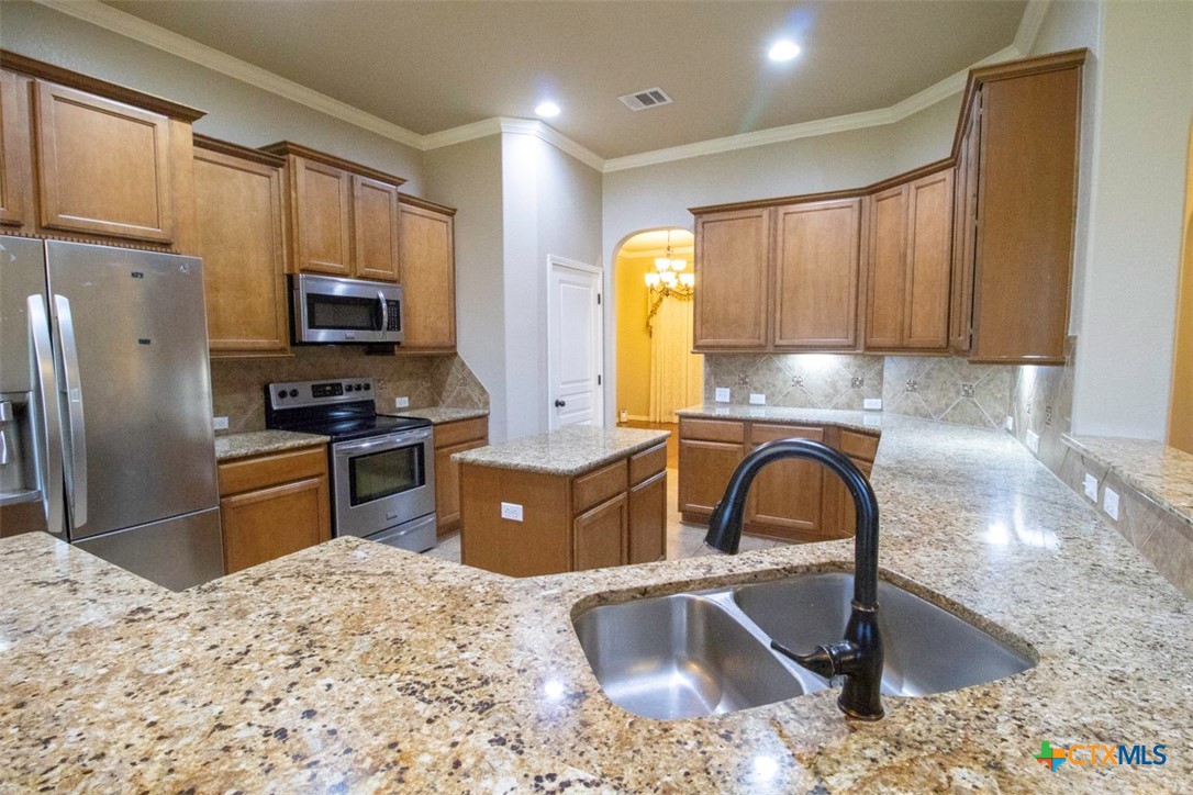 7022 Valley Mist Drive Temple, TX 76502 - Photo 9 of 36 a kitchen with stainless steel appliances kitchen island granite countertop a sink stove and refrigerator