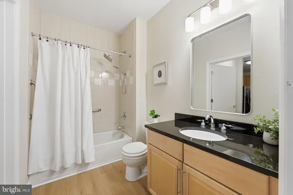 a bathroom with a granite countertop sink a toilet and a shower