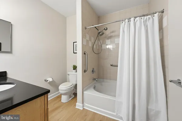 a bathroom with a granite countertop bathtub shower sink vanity and toilet