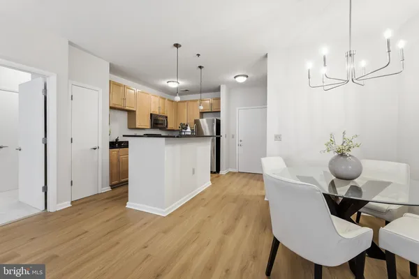 a kitchen with kitchen island stainless steel appliances a dining table chairs sink and microwave
