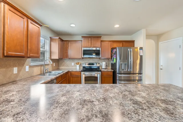 a large kitchen with granite countertop a stove a sink and a refrigerator