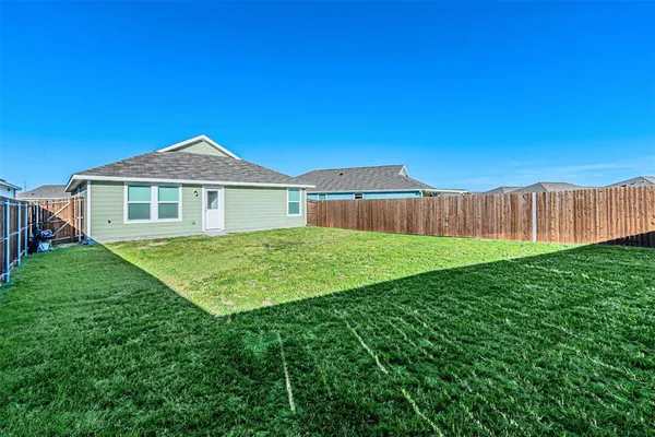 a view of a house with a big yard plants and large tree
