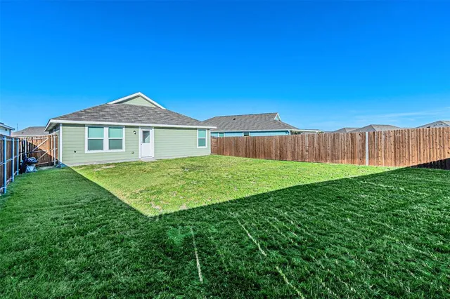 a view of a house with a big yard plants and large tree