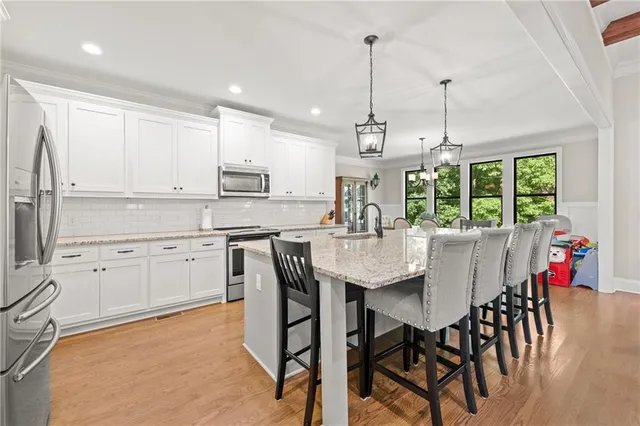 a kitchen with stainless steel appliances kitchen island granite countertop a dining table chairs and white cabinets