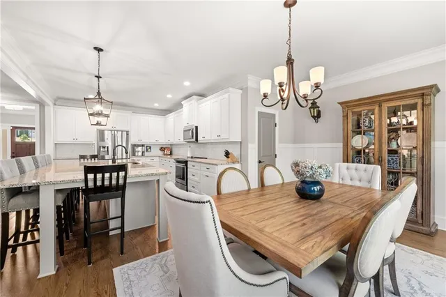 a dining room with wooden floor a chandelier a wooden table and chairs
