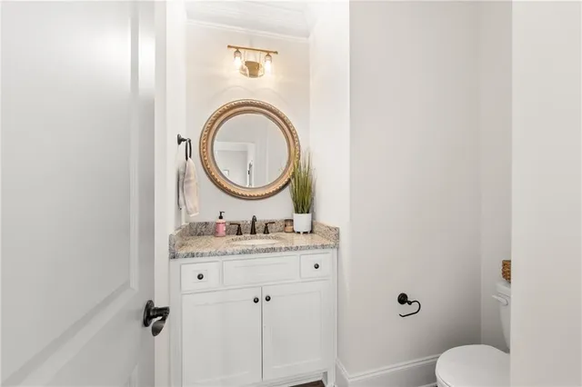 a bathroom with a granite countertop sink mirror vanity and toilet