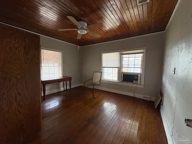 a view of empty room with wooden floor and fan