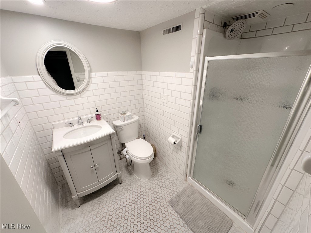 8145 Chagrin Road Chagrin Falls, OH 44023 - Photo 34 of 40 Bathroom with a shower stall, tile walls, vanity, a textured ceiling, and wainscoting
