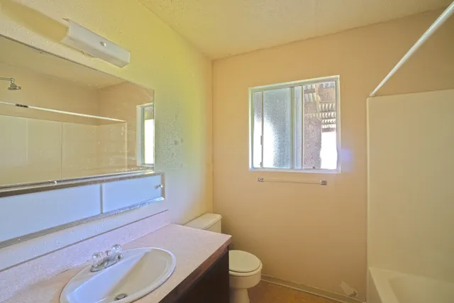 a bathroom with a granite countertop toilet sink and mirror