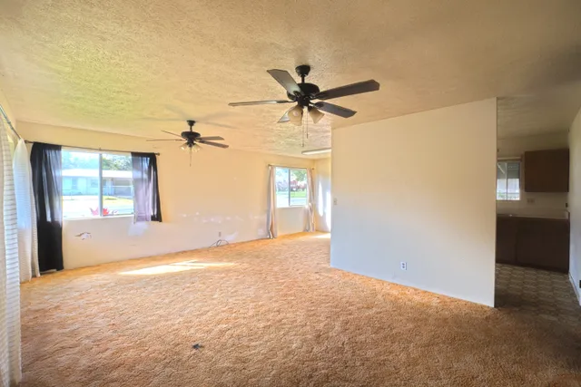 a view of a big room with chandelier fan and windows