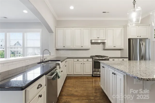 a kitchen with stainless steel appliances granite countertop a refrigerator a sink dishwasher a stove and white countertops with wooden floor