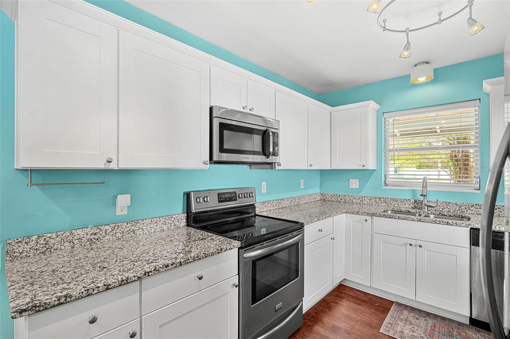 2923 Conway Gardens Road Orlando, FL 32806 - Photo 24 of 28 a kitchen with granite countertop white cabinets and white appliances