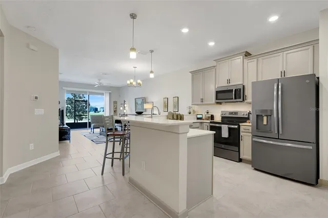 a kitchen with a refrigerator a microwave oven a sink a dining table and chairs